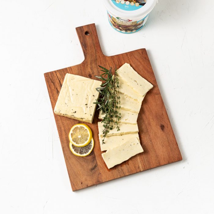 Halloumi Cheese styled with herbs and sliced lemon on a board. | Featured image for Fresco Cheese.